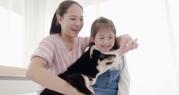 Mother and daughter playing with black dog on bed (13)