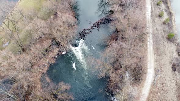 Small river dam and rapids on scenic, idyllic, willow tree lined river in winter in rural countrysid alt