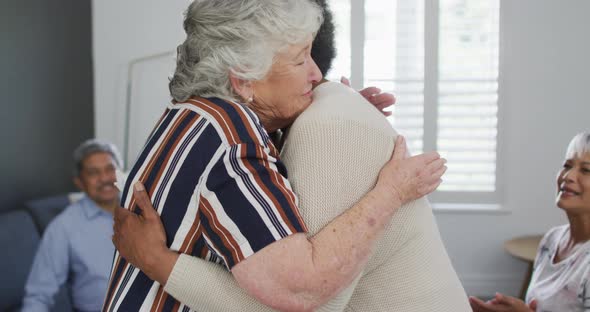 Caucasian senior woman giving support to african american female friend on meeting alt