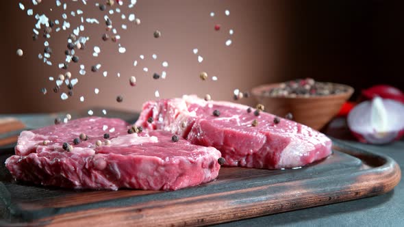 Super Slow Motion Shot of Falling Pepper and Salt on Fresh Meat at 1000Fps. alt