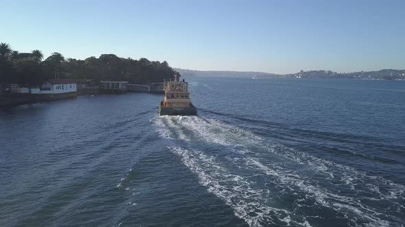 Sydney ferry docking at suburb port in summer, low aerial follow alt