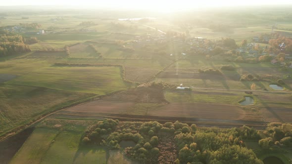 AERIAL: Beautiful Sunny Vast Fields in Summer with Small Town in Background