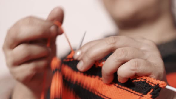 Woman's hands doing knit work tie-up hand work with red and black wool. alt
