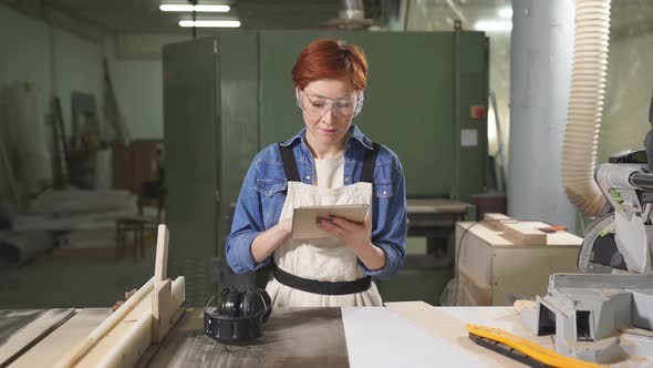 Beautiful Caucasian Female Carpenter Using Digital Tablet Working On Design Project