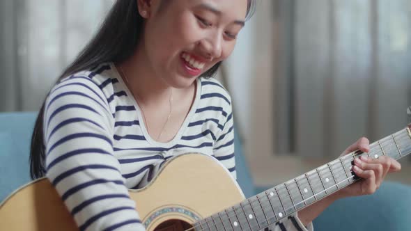 Close Up Of Asian Woman Composer With A Guitar Celebrating For Finishing Composing Music On Paper At alt