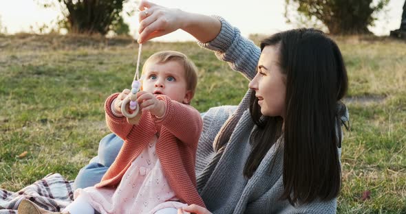 Mother and a Small Daughter, Spends Time Together in a City Park on a Picnic. Young Woman and Little