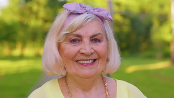 Cheerful Lovely Senior Old Grayhaired Grandmother in Casual Yellow Blouse on Summer Park Background alt
