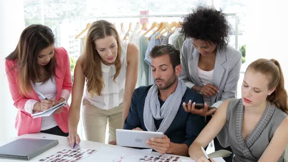 Busy Fashion Design Team Working Together at Table alt