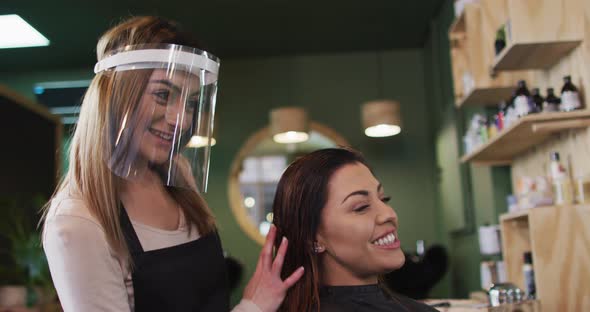 Female hairdresser running her fingers through hair of female customer alt