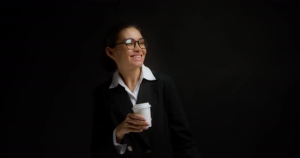 Brunette in Glasses and Office Clothes Drinks Coffee From a White Paper Cup alt