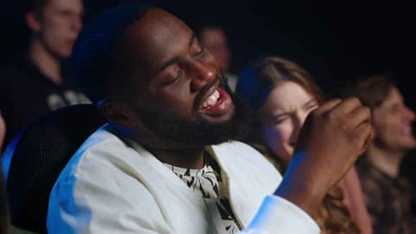 Cheerful People Watching Film in Cinema. Joyful Friends Laughing in Dark Hall. alt