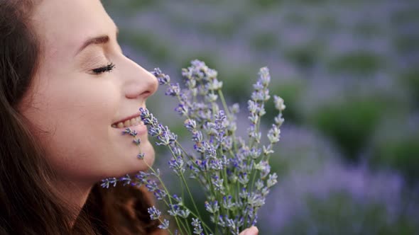 Closeup Beautiful Female Sniffing Lavender Flowers in a Summer Bright Dress Lavander Field alt