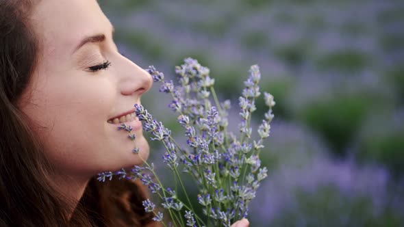 Closeup Beautiful Female Sniffing Lavender Flowers in a Summer Bright Dress Lavander Field
