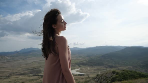 A Video Portrait of a Girl Looks at the Camera in a Pink Dress Enjoying the Sun