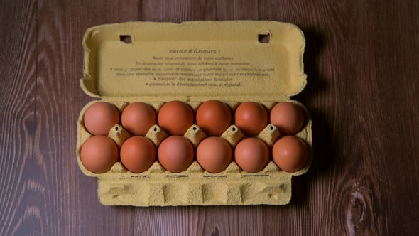 Filling a box with eggs in a cardboard package on brown background, animation stop motion