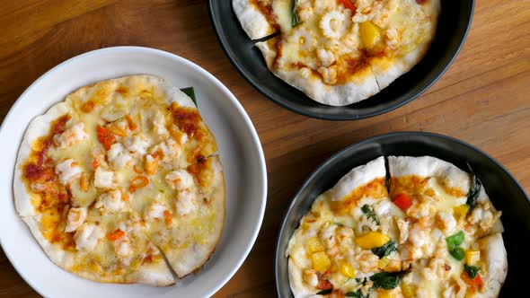 Top View of Assortment of Small Pizzas in Plates on Wooden Background alt