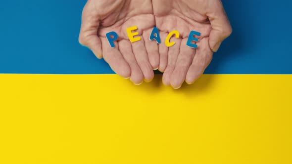 Man Holding a Peace Inscription in the Colors of the Ukrainian Flag alt