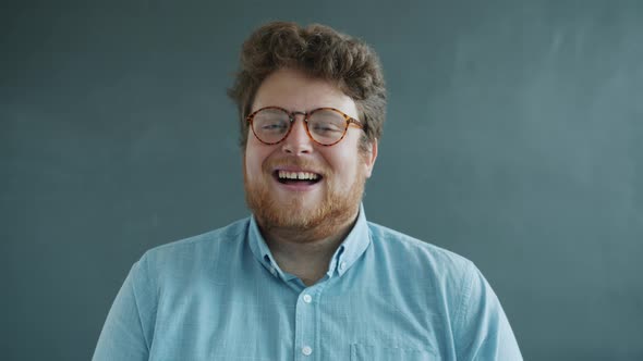 Portrait of Joyful Man Laughing Looking at Camera Then Making Funny Faces on Gray Background alt