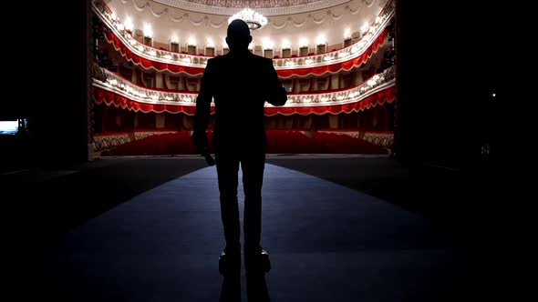 Actor walks on a scene in front of empty auditorium. Financial losses of organizers in entertainment alt