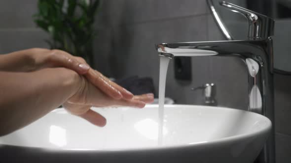 Woman is washing hands with soap and warm water, rubbing fingers washing frequently alt