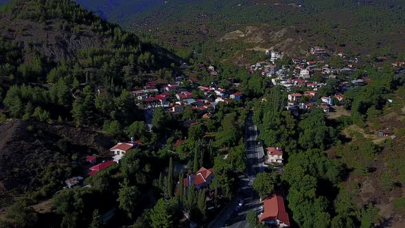 Aerial establishing shot of greek church and village nestled in vally alt