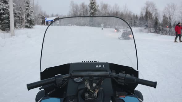 Shooting From the Driver's Seat Like a Column of Snowmobiles with Tourists Turns Onto a Forest Road alt