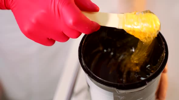 Handyman in Red Gloves Stirs Sugar Paste Before Removing Unwanted Hair alt