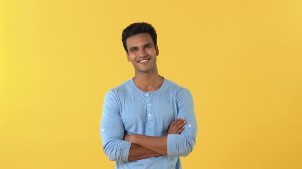 Handsome young Indian man smiling and looking at camera with crossed arm gesture