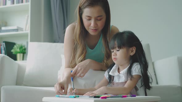 Home study concept : A Beautiful single Asian mother teaching her daughter to read, write and drawin alt