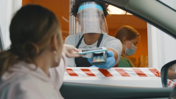 Woman Driver Paying for Order in Terminal of Fast Food Cafe From Car Window. alt