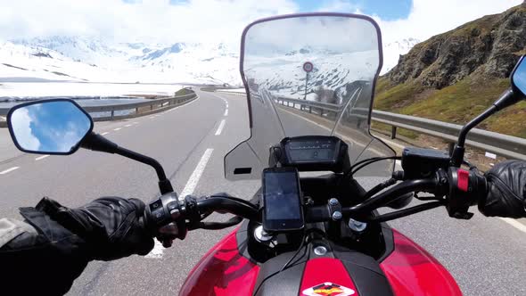 Motorcyclist Rides on Beautiful Landscape Snowy Mountain Road Near Switzerland Alps alt