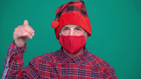 Portrait of Old Man Wearing Christmas Red Hat and Medical Protective Face Mask Showing Thumbs Up and