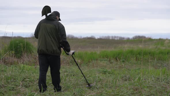 Treasure Hunter with Metal Detector and Shovel Scanning Ground in Summer Forest