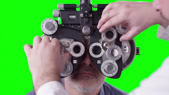 Optometrist using Phoropter for eye exam turning dials alt