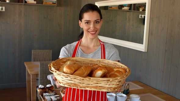 Portrait of female baker holding baguettes in basket alt