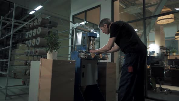 Sewing workshop worker sets up an automated machine for the production of high-quality rope