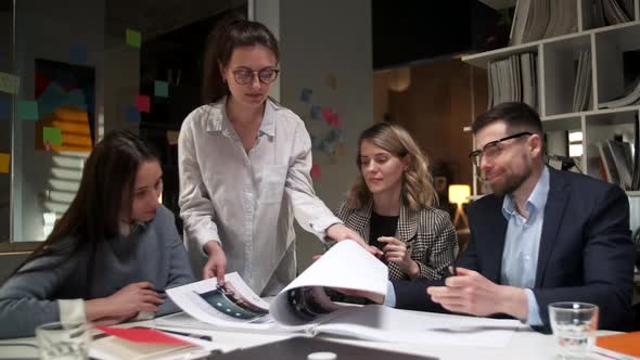 Team Of Creative Designers Are Looking At The Project Magazine, Talking About Them, Sitting Together alt