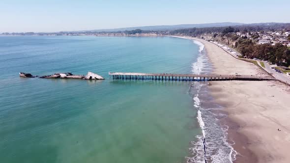 Sunken concrete freighter SS Palo Alto and wooden pier, aerial flying forward view. Sandy California alt