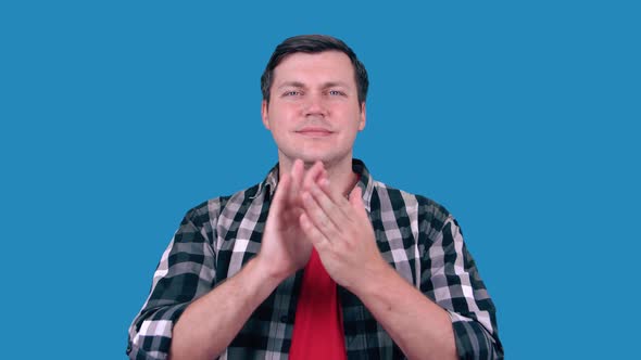 Handsome man on blue background claps his hands and applauds happy and joyful
