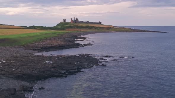 Iconic english Dunstanburgh Castle at sunset, Northumberland, England, UK. Aerial drone view alt