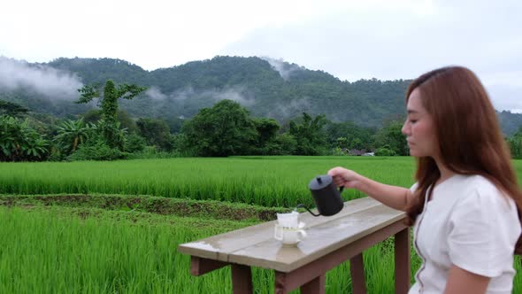 Blurred of a woman making drip coffee in the rice field with a beautiful nature view