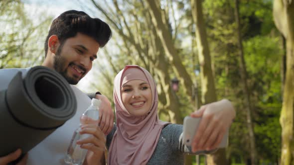 Cheerful Muslim Man and Woman in Hijab Taking Self Portrait on Smartphone While alt