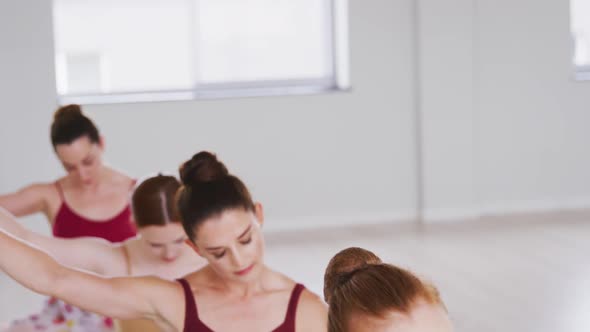 Caucasian ballet female dancers stretching up with a barre before a ballet class alt