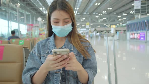 asian tourist traveller weaar protective face mask sit wait in airport terminal