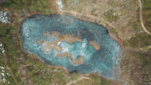AERIAL: Bright Blue Ice Swamp Lake in Forest in Lithuania