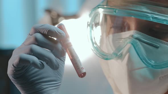 Male Doctor Holds Blood Test Tube To Check a Blood Sample for the COVID-19 Virus alt