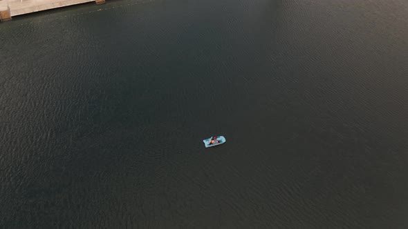 Aerial shot of people in a paddle boat on a green lake- alt