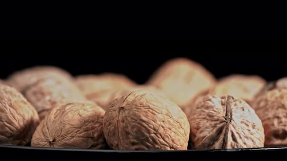 Lot of Walnuts in the Shell are Spinning on a Black Background alt