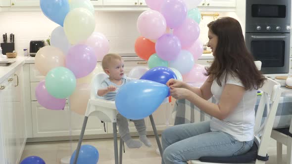 Mother and Baby are Preparing to Celebrate Children Birthday Blowing Up Balloons to Decorate Home alt