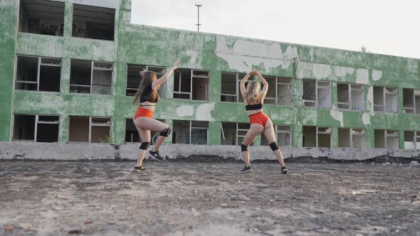 Two Girls Dance Twerk on the Roof of an Abandoned Building. Girls in Red Shorts and Checkered Tights